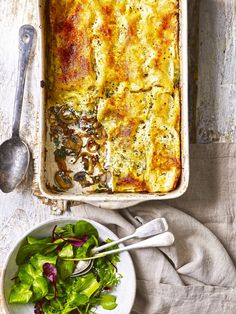 a casserole dish with spinach and cheese next to a salad on a plate