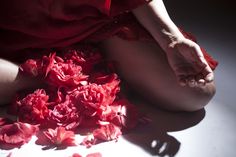 a woman is sitting on the floor with red flowers