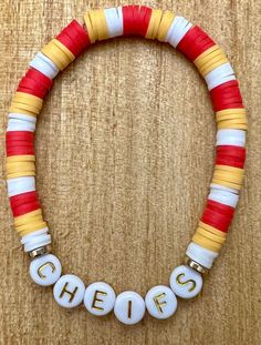 a red, white and yellow beaded necklace with the word chees on it