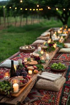 a long table with candles and food on it in the middle of a grassy field