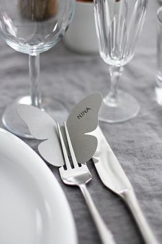 a table setting with silverware and butterfly shaped utensils on top of it