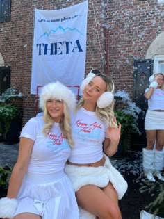 two women dressed in white posing for the camera with snow on their heads and feet