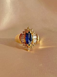 Vintage 14k sapphire diamond baguette ring featuring a marquise cut sapphire central to a halo of diamonds--10 round cuts and 10 baguette cuts.  Great vintage condition Size: 7.75 resizable* Weight: 7 grams Sapphire: 4.8 x 11.8 mm marquise cut Diamond: 10 round cuts and 10 baguette cuts Hallmarks: 14K BH Please note, vintage and antique jewelry may come with imperfections commensurate of their age. To see more photos and videos of this piece, visit my Instagram: www.instagram.com/23carat PLEASE Diamond Baguette Ring, Vintage Sapphire Ring, Diamond Baguette, Baguette Diamond Rings, Marquise Ring, Baguette Ring, Vintage Sapphire, Birthday Ring, Marquise Cut Diamond