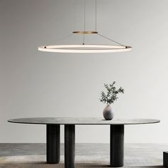 a round table with a vase on it and lights hanging from the ceiling over it