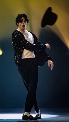 a male in a black jacket and white shirt is dancing