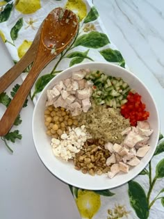 a white bowl filled with food next to a wooden spoon on top of a table