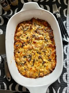 a casserole dish with cheese and mushrooms in it on a black and white tablecloth