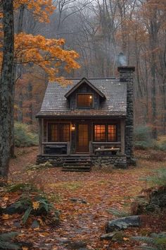 a small cabin in the woods surrounded by trees and leaves with fall foliage around it