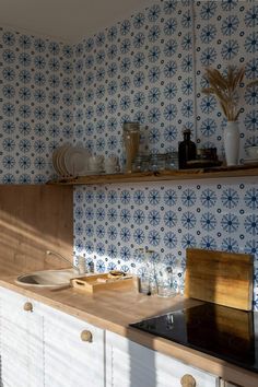 a kitchen with blue and white tiles on the wall next to a stove top oven