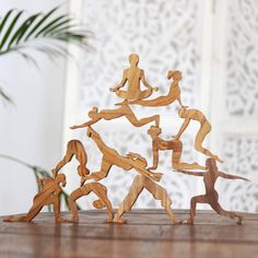 several wooden figurines are arranged in the shape of people doing different activities on a table