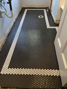 a bathroom that has a black and white tile floor in the middle of it, next to a door