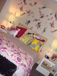 a bedroom with floral wallpaper and purple bedding