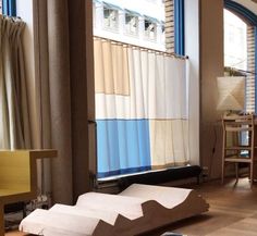 a living room filled with furniture next to a window covered in blue and white curtains