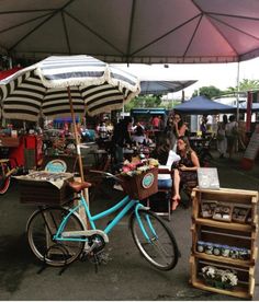 a blue bicycle parked under an umbrella at a market