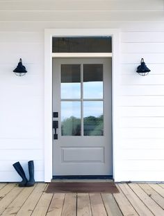 a white door with two black lamps on the side of it and a wooden floor