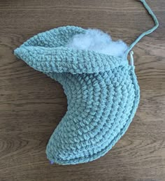 a crocheted blue bag with a white fur inside sitting on a wooden surface