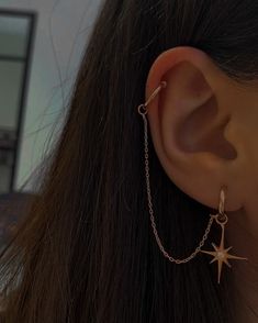 a close up of a person's ear with a star and chain on it