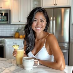 a woman sitting at a kitchen counter holding a drink