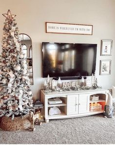 a living room decorated for christmas with a large tv and white tree in the corner