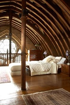 a bedroom with wooden beams and white bedding in the middle of an open floor plan