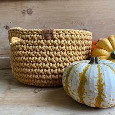 three pumpkins sitting next to each other on a wooden table with a basket in the middle