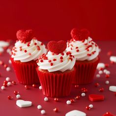 three cupcakes with white frosting and red sprinkles