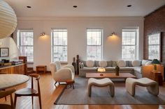 a living room filled with lots of furniture and large windows in the wall behind it