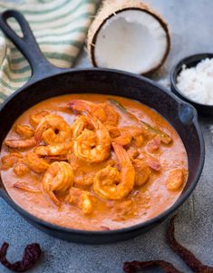 a skillet filled with shrimp and rice next to a wooden spoon on top of a table