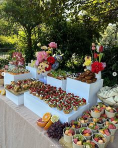 there are many different types of desserts on the table with flowers and fruit in bowls