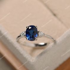 an oval blue sapphire and diamond ring in a box