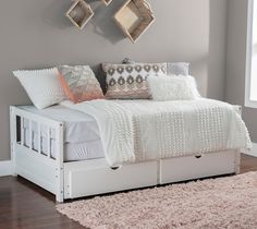 a white bed sitting in a bedroom on top of a hard wood floor next to a window