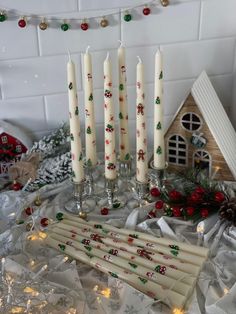 five candles are sitting next to each other on a table with christmas decorations around them