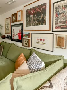 a living room filled with green couches and framed pictures on the wall above them