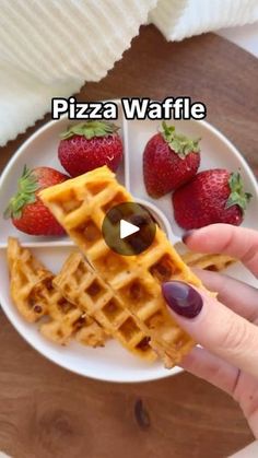 a person is holding a waffle on a plate with strawberries