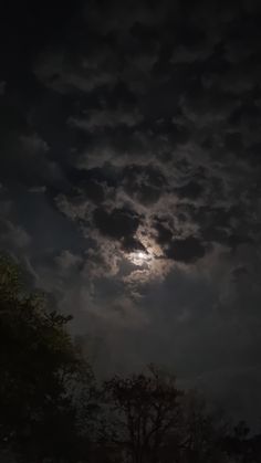 the full moon shines brightly through dark clouds