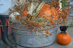 pumpkins and gourds are sitting in a bucket on the ground next to boots