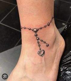 a woman's foot with a chain and heart tattoo on it, which is attached to the ankle