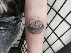 a woman's arm with a mountain and moon tattoo on the left inner forearm