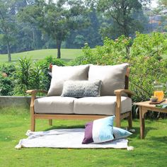 a couch sitting on top of a lush green field next to a wooden table and chair