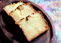 two slices of cake sitting on top of a wooden plate next to another piece of bread