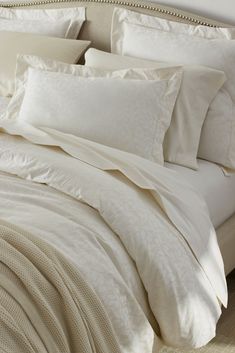 a bed with white sheets and pillows on top of it