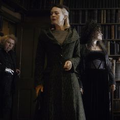 two women standing next to each other in front of bookshelves