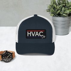 the hvac trucker hat is next to a watch and potted plant on a table