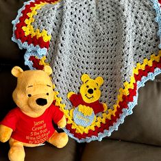 a crocheted winnie the pooh blanket next to a teddy bear on a couch