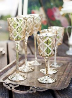 four wine glasses sitting on top of a wooden tray next to another glass cup and saucer