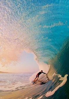 a man riding a wave on top of a surfboard in the ocean under a blue sky