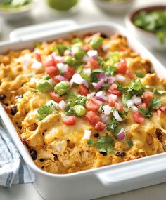 a white casserole dish filled with mexican food and garnished with cilantro