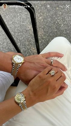 two people holding each other's hands while sitting down with their watches on their wrist