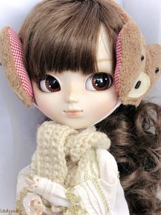 a close up of a doll with long hair and a teddy bear on her head