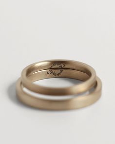 two gold wedding bands on a white surface